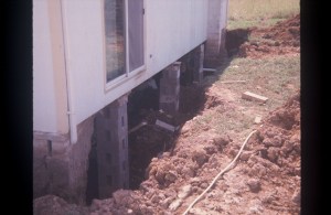 Bricks bracing up a house where the foundation used to be.